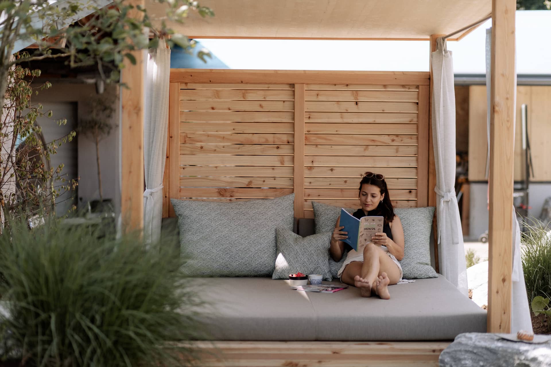 Frau ließt ein Buch in der Loungeliege im Garten