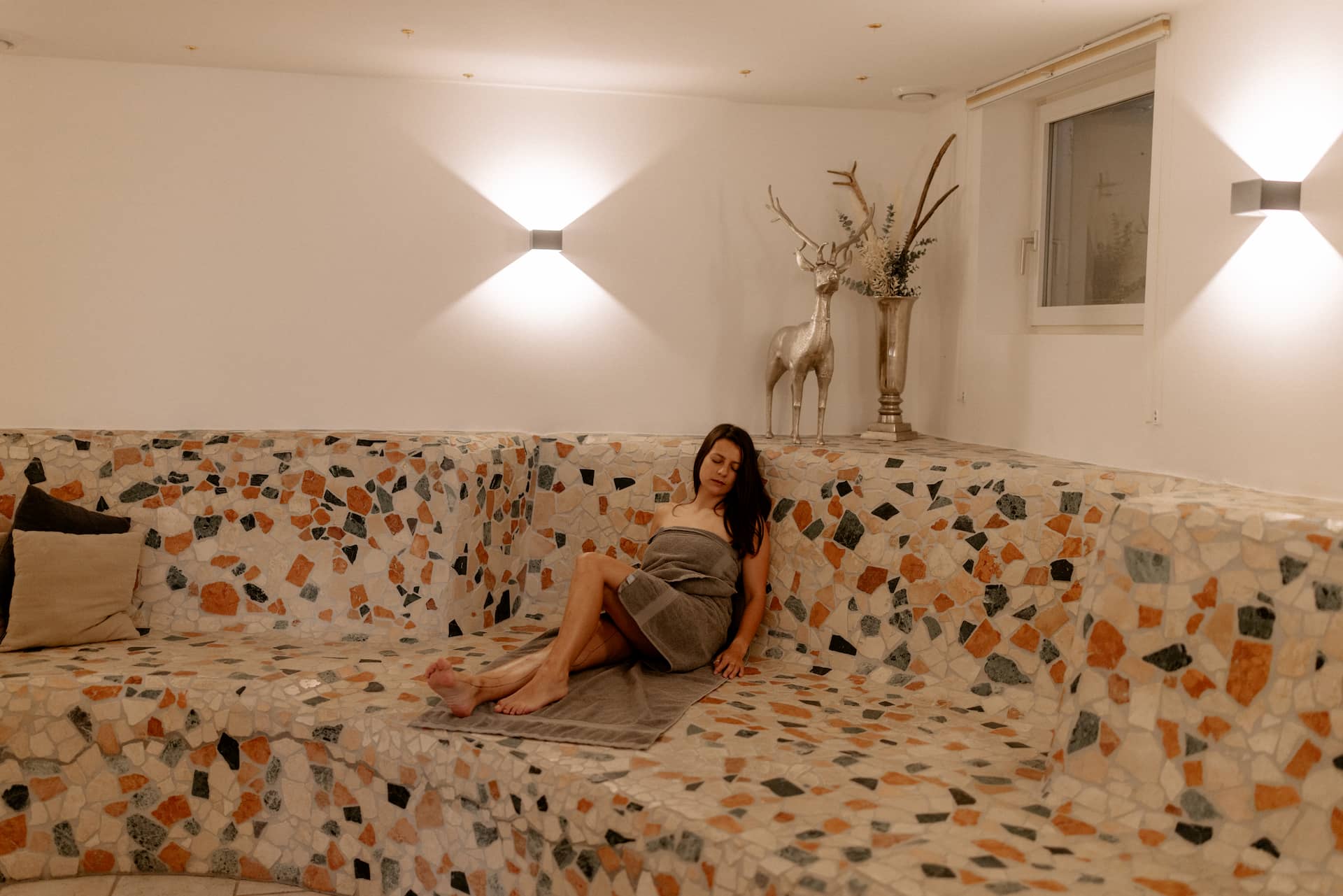 Frau genießt die angenehme Wärmebank im Wellnessbereich unseres Hotels in Flachau